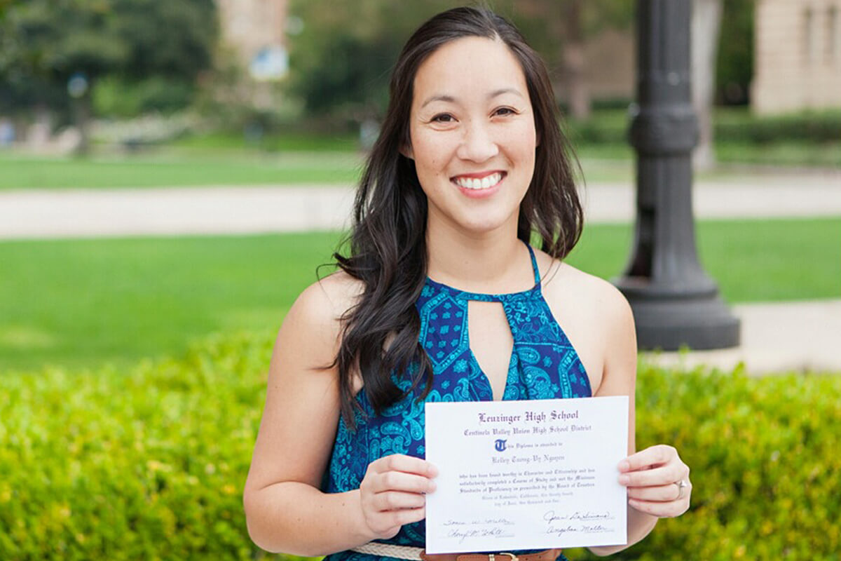 Dr. Kelley Le holding her high school diploma at UCLA.