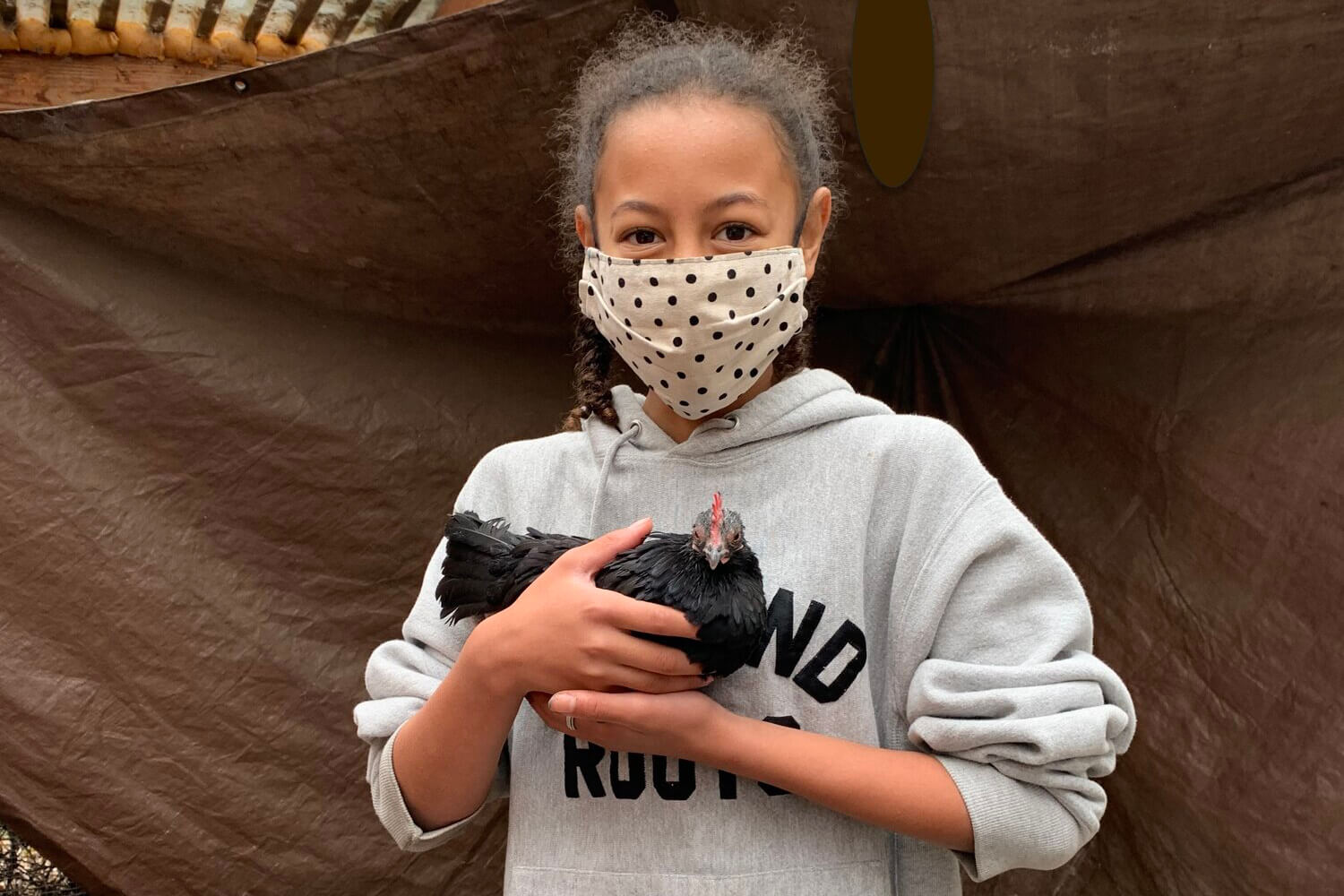 Girl with a face mask holding a chicken